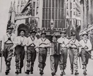 6 morris men and a piano accordion player in front of Bath Abbey in 1954