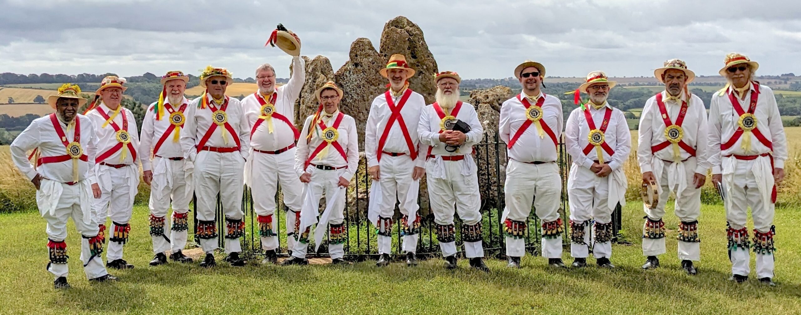 Group of Morris dancers in kit in front of Rollright Stone.